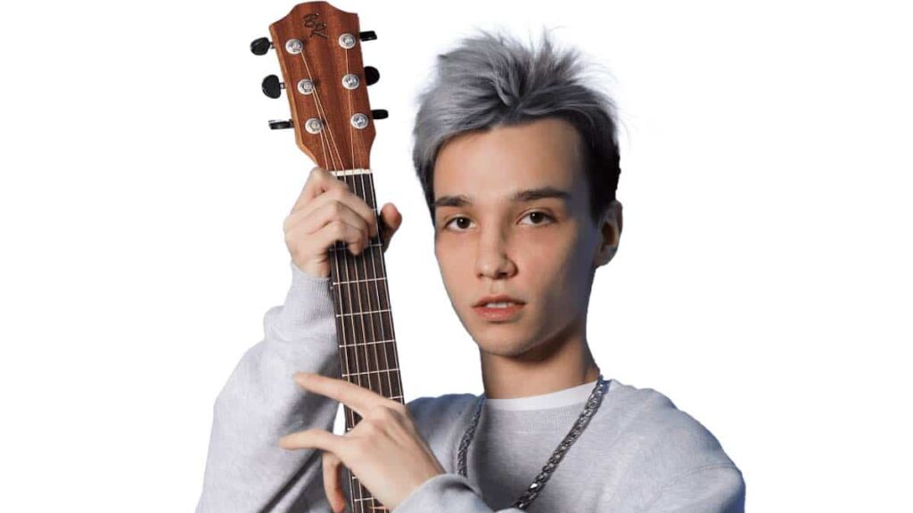 Akstar biography portrait — posing with a guitar for a studio session.