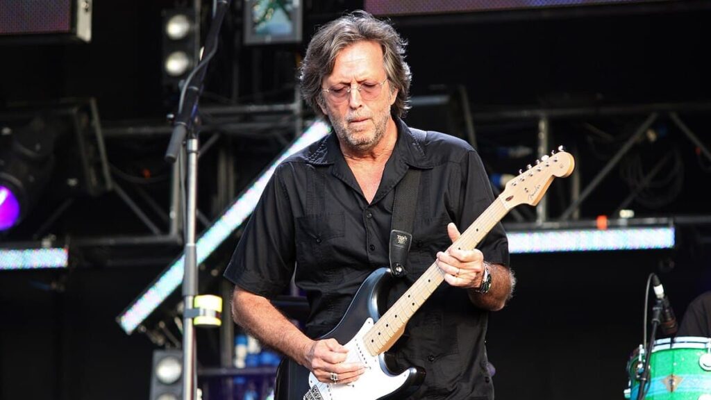 Eric Clapton biography portrait — performing on stage with a guitar.