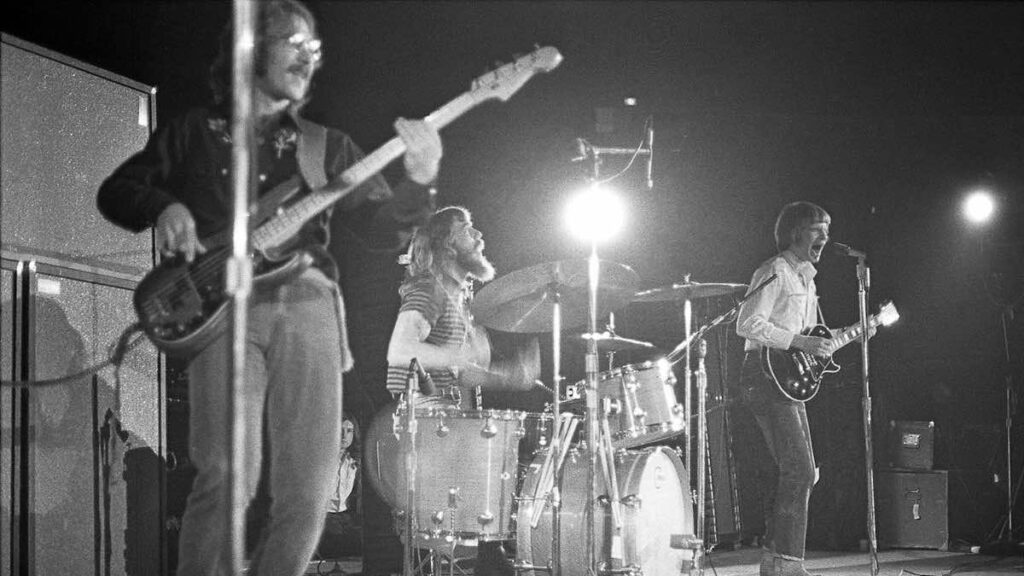 Creedence Clearwater Revival biography portrait — rock band members playing instruments on stage.