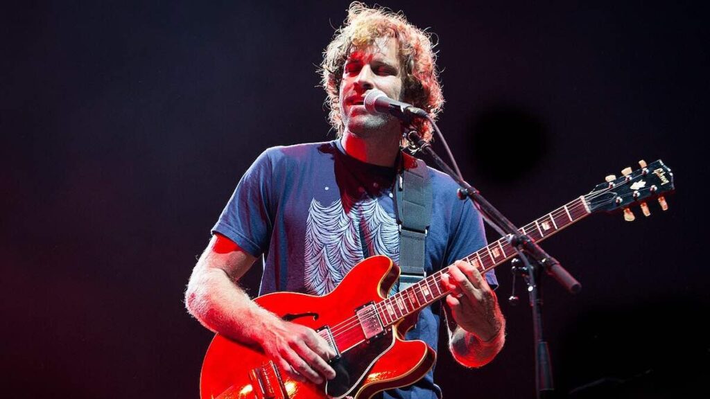 Jack Johnson biography portrait — performing with guitar on stage.