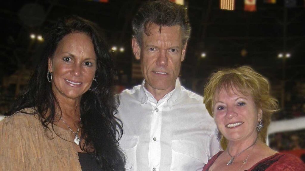 Randy Travis biography portrait — performing with acoustic guitar on stage.