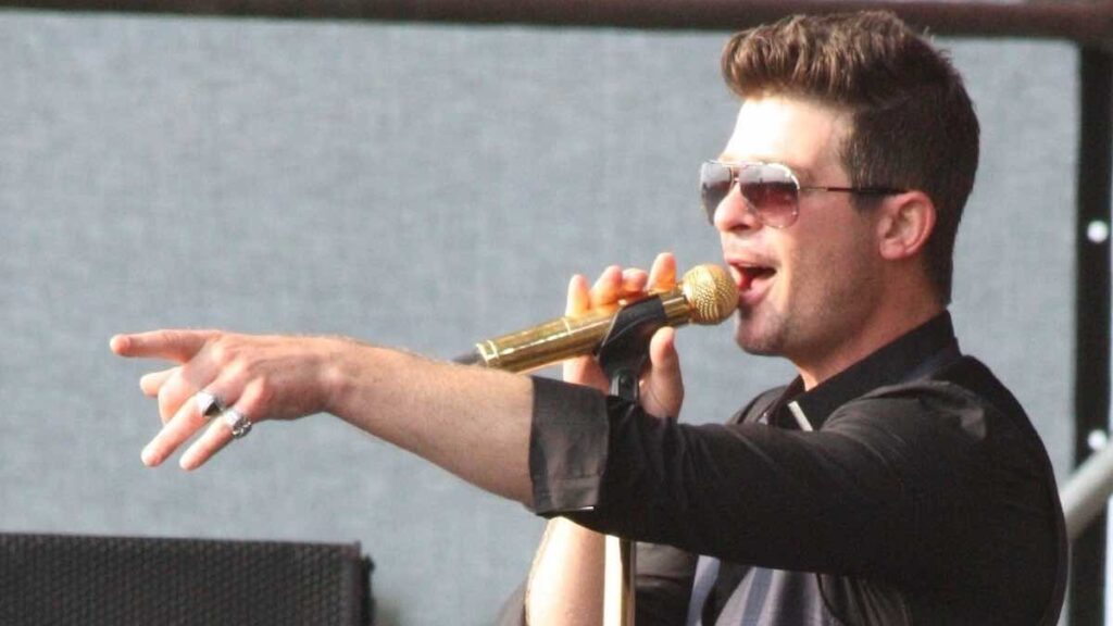 Robin Thicke biography portrait — posing in a black suit in 2014.