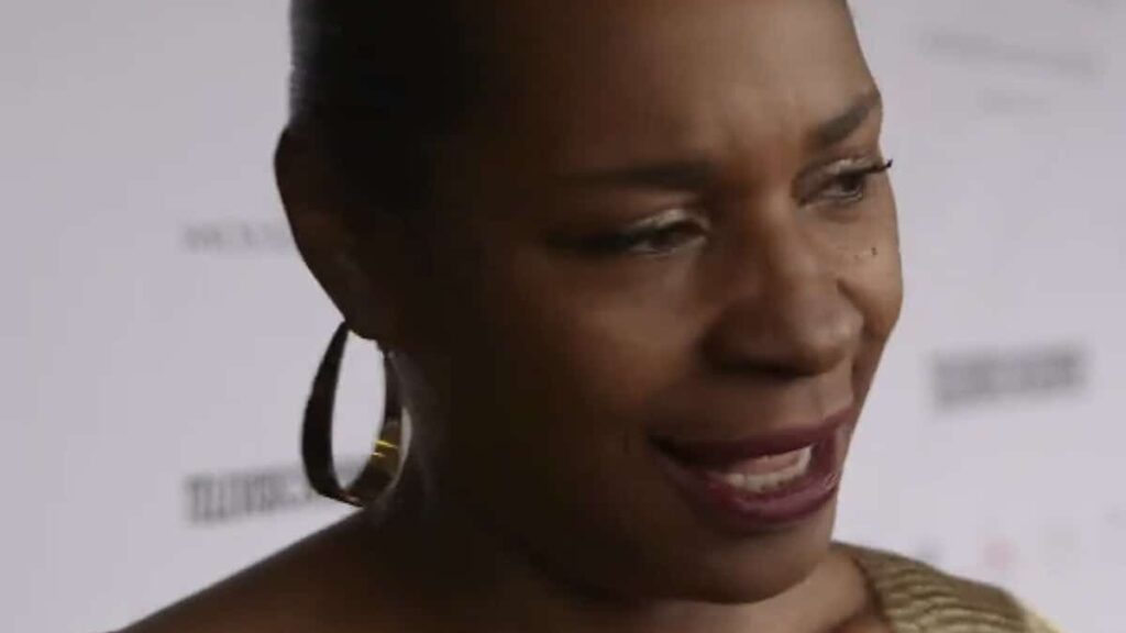 Sonique biography portrait — smiling brightly on the red carpet at an awards ceremony.