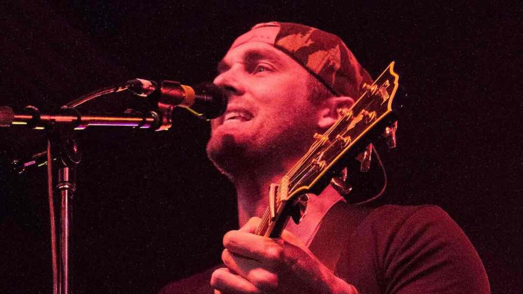 Brett Young biography portrait — performing on stage with a guitar in 2015.